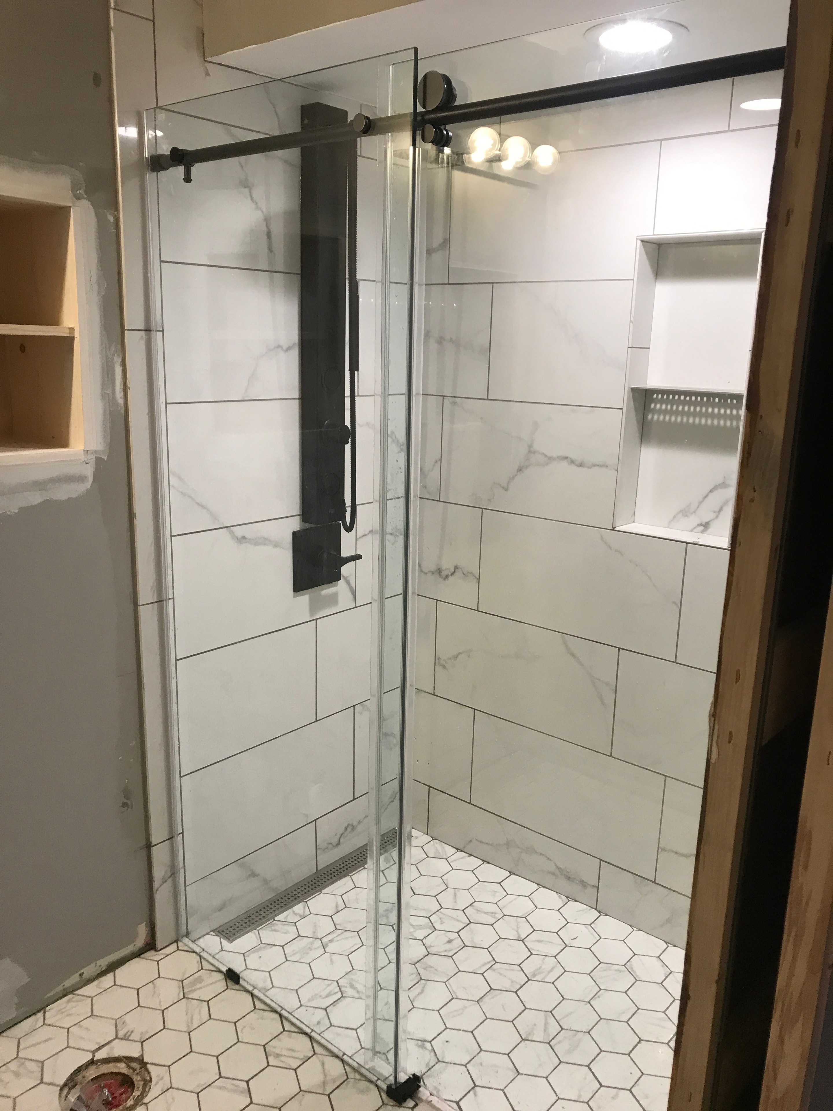 Bathroom after remodel — marble tile, glass shower, modern fixtures